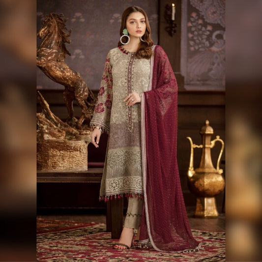 Woman in traditional embroidered outfit with a maroon dupatta in an ornate room.