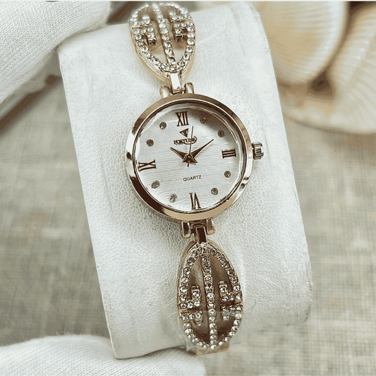 Gold watch with decorative chain on a white cushion