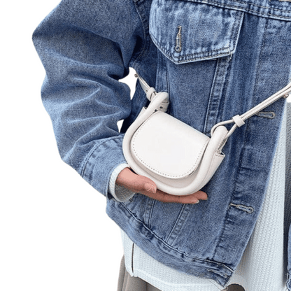 Person holding a white crossbody bag with a denim jacket