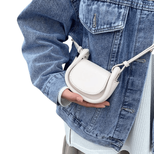 Person holding a white crossbody bag with a denim jacket