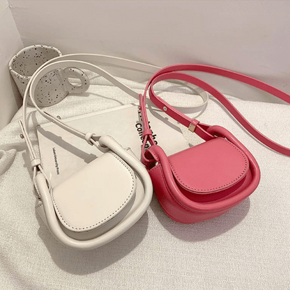 Two small handbags, one beige and one pink, on a light surface.