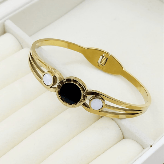 Gold bangle with black central stone and white stones on the sides

