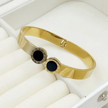 Gold bangle with black central stone and white stones on the sides