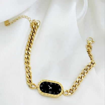 Gold chain bracelet with a black clock face on a white background