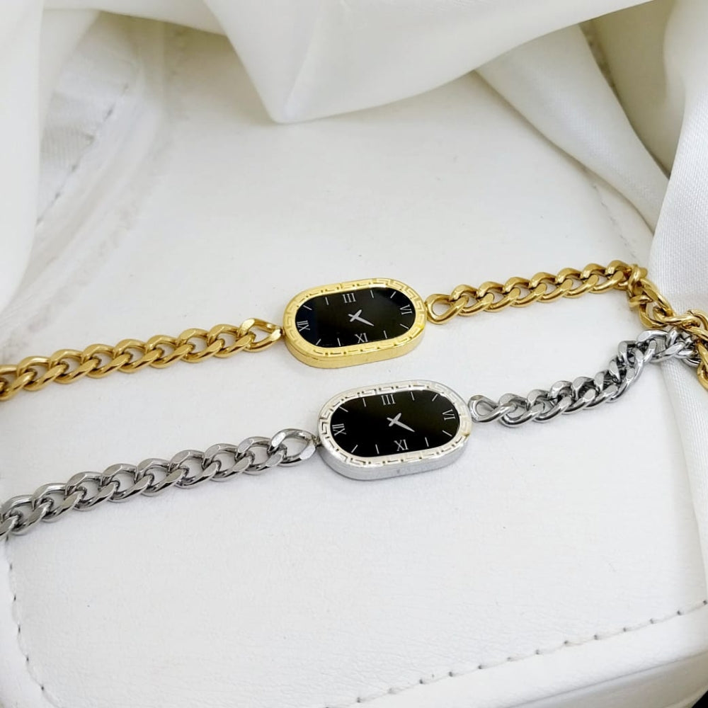 Two chain bracelets with clock faces on a white fabric background