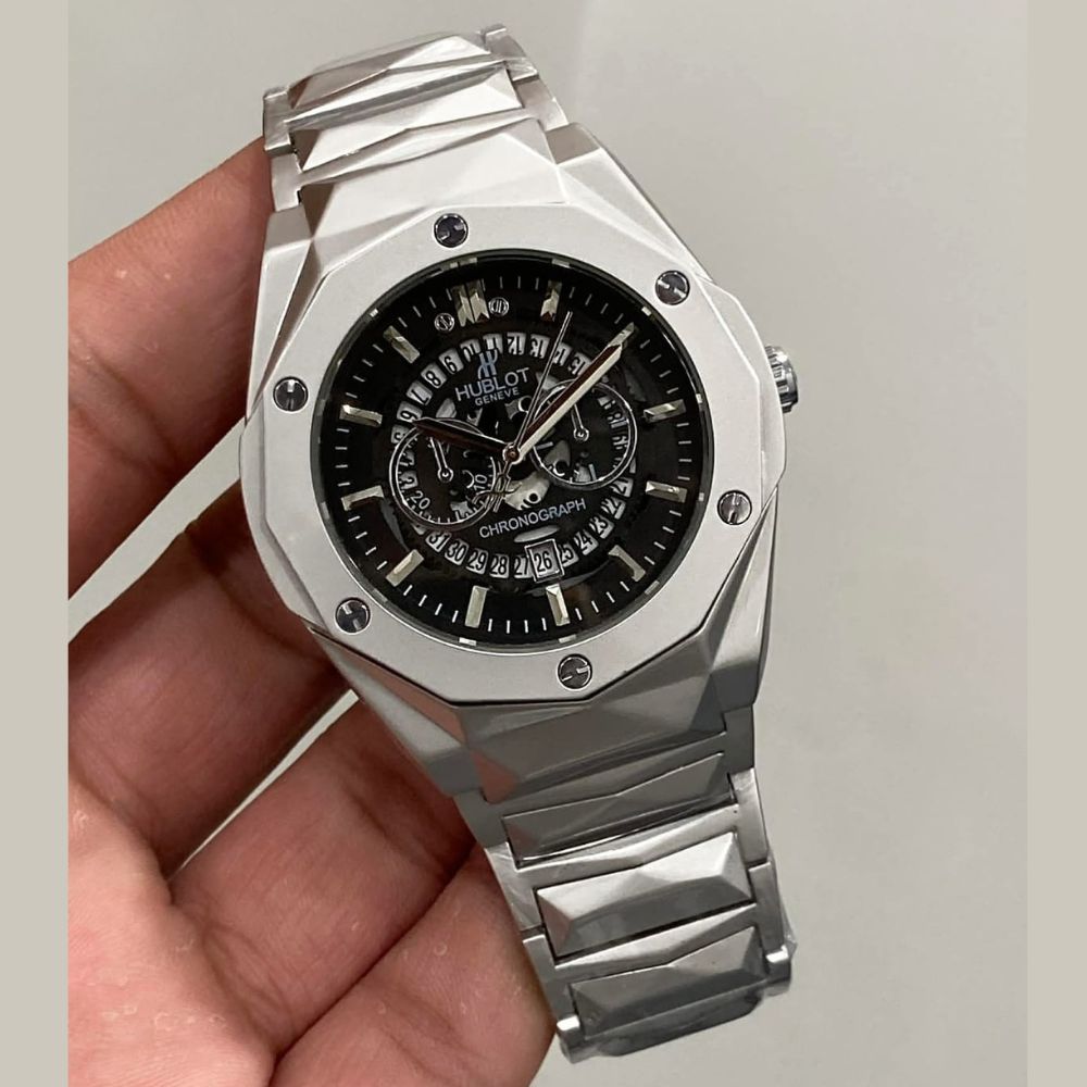 Silver watch with black face held in a hand against a light gray background