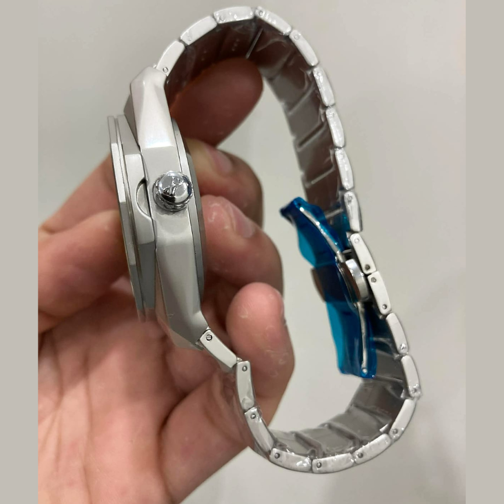 Silver watch with a broken band held by a hand against a plain background