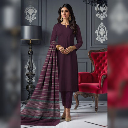 Woman in a purple traditional outfit standing in an elegant room with a red chair and decorative wall.