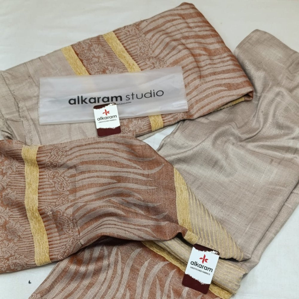 Textile products with 'alkaram studio' branding on a white surface