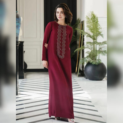 Woman wearing a burgundy dress with intricate detailing in a modern indoor setting.