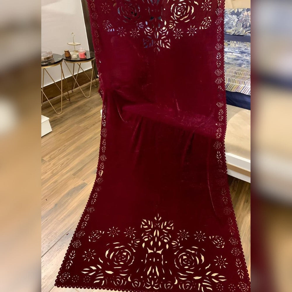 Red lace fabric with floral patterns on a wooden floor.