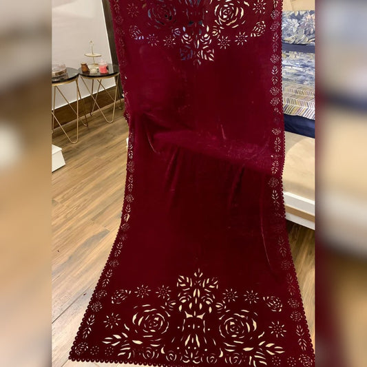 Red lace fabric with floral patterns on a wooden floor.