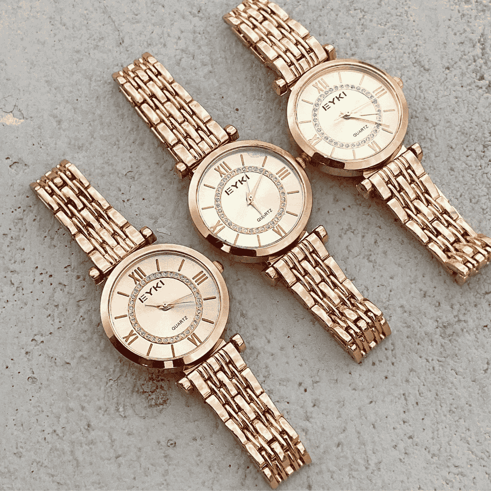 Two rose gold watches with textured bands on a gray surface