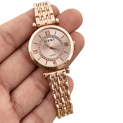 Rose gold watch with chain strap held in a hand against a white background