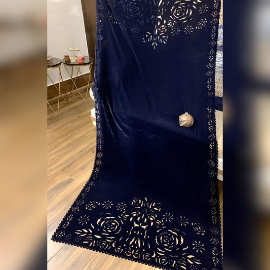 Navy blue fabric with gold floral embroidery on a wooden floor.