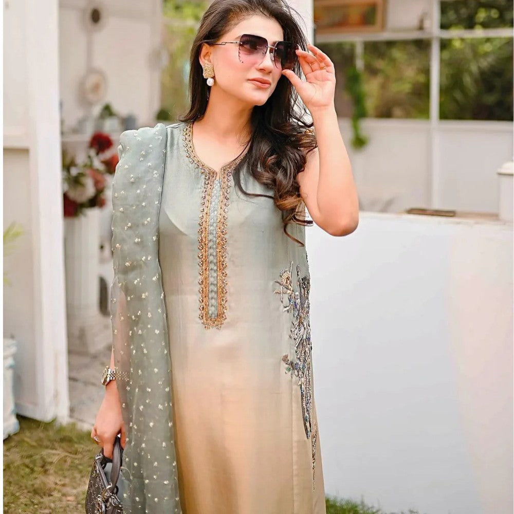 Woman wearing a light green and beige traditional outfit with sunglasses outdoors.