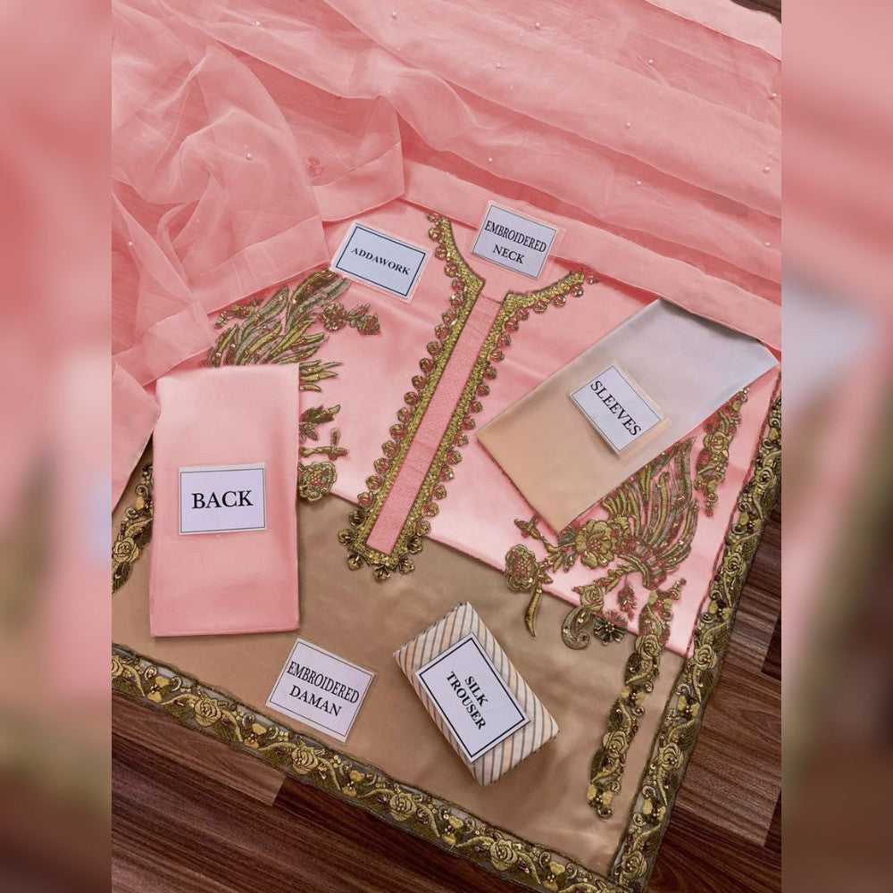 Embroidered pink and gold fabric pieces on a wooden board with labels.