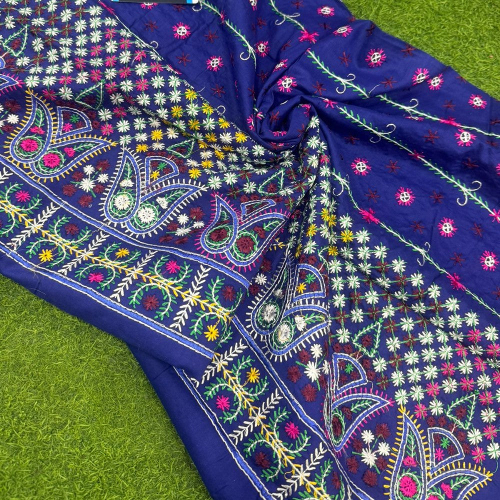 Colorful embroidered fabric with intricate patterns on a green grass background