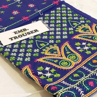 Embroidered fabric with colorful patterns on a blue background, labeled 'Emb. Trouser'.