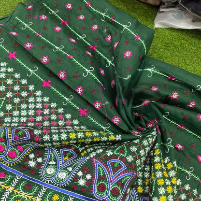 Green fabric with colorful embroidery patterns on a green surface
