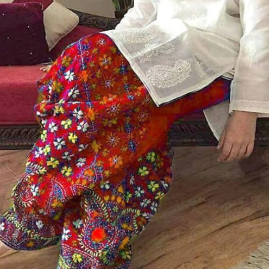 Colorful floral-patterned fabric draped over a person sitting on a wooden floor.