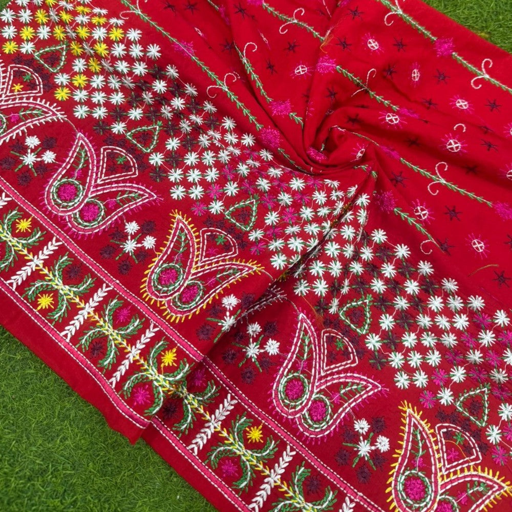 Red fabric with intricate white, green, and pink patterns on a green background