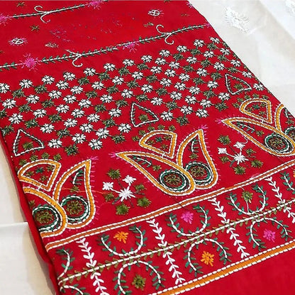 Red fabric with intricate white, green, and orange patterns on a white background