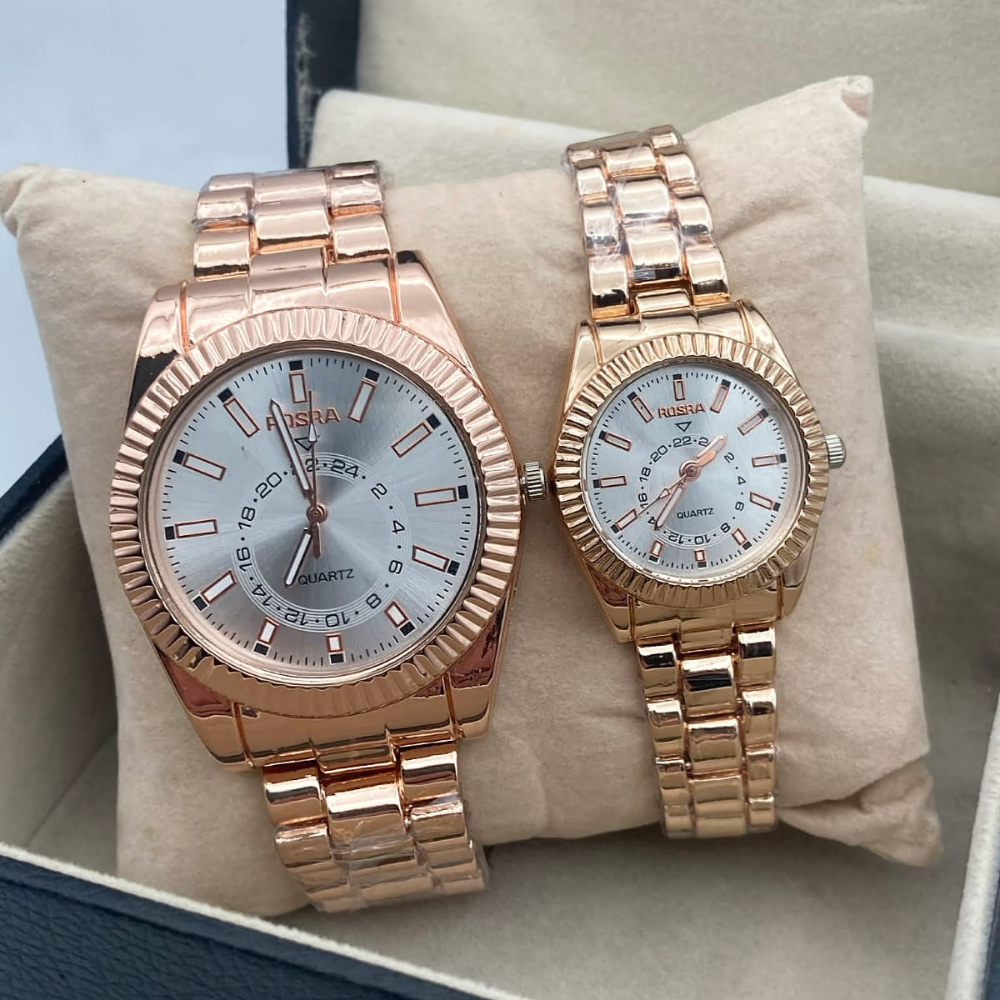 Two rose gold watches on a beige cushion with a light blue background