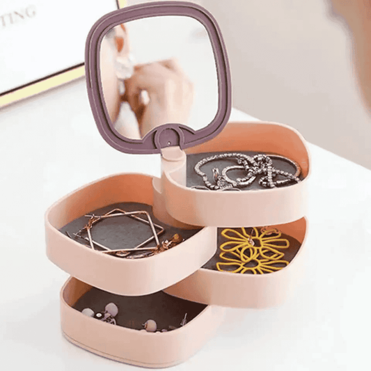 Pink jewelry organizer with mirror lid containing necklaces and earrings on a white background