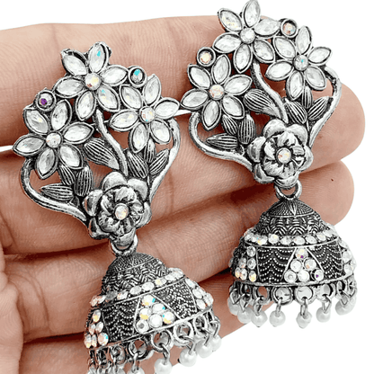 Close-up of silver earrings being held in hand to show size and detail