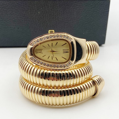 Gold spiral clock with decorative design on a white surface