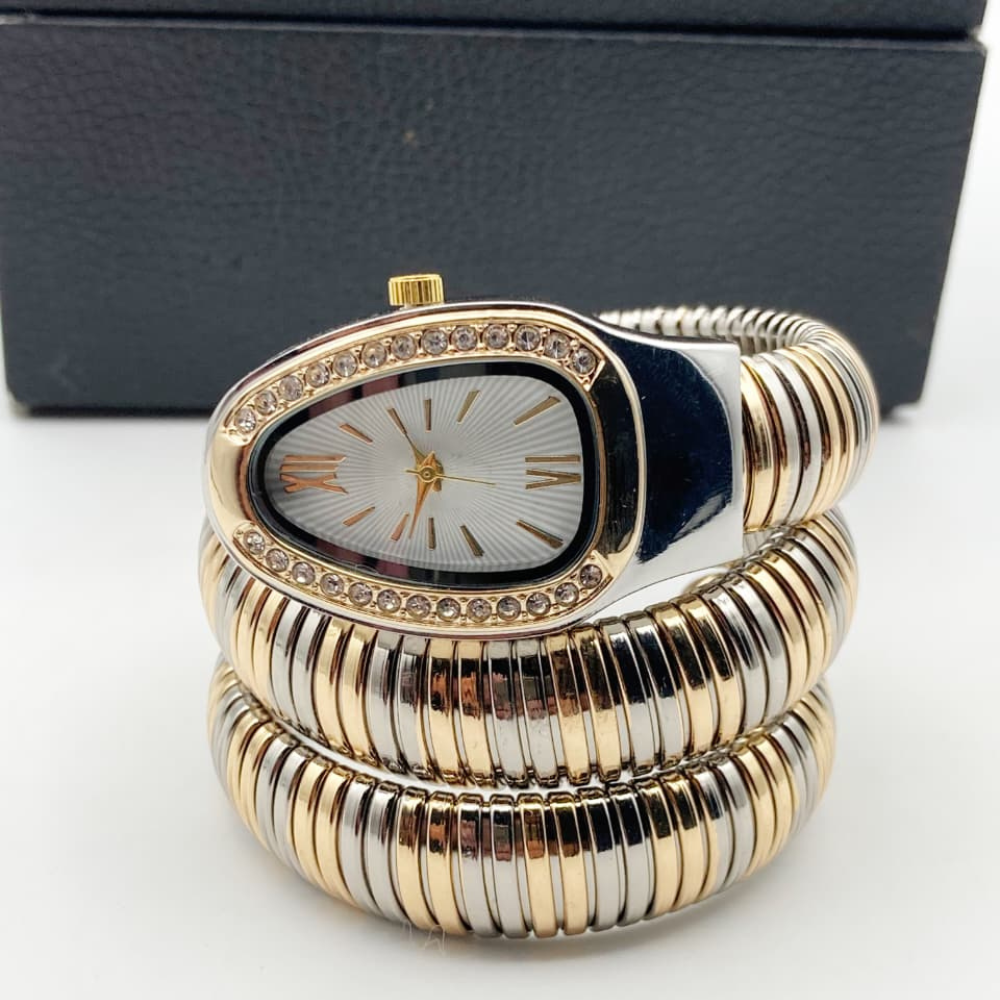 Gold and silver bracelet with a watch face on a white background